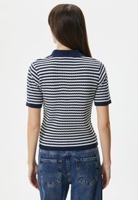 Marineblå og hvid stribet kortærmet polo skjorte med ribbede krave og kant, tætsiddende design og struktureret strikket stof.