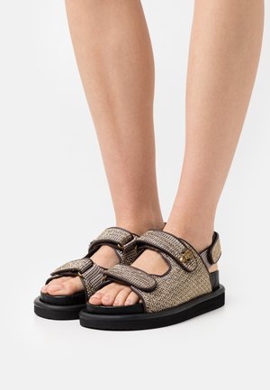 Brązowo-złote plecione sandały z regulowanymi paskami, teksturowaną cholewką i grubą czarną podeszwą. Zdobione dekoracyjnym złotym akcentem.