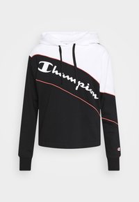 Svart och vit huvtröja med röda accenter. Har en djärv "Champion"-logotyp och långa ärmar med ribbade manschetter. Slät tygkvalitet.