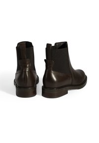 Bruine leren enkellaarsjes met elastische zijkanten, ronde neus en een gestructureerde hak. Glad afwerking met stevige zolen.
