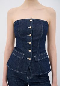 Top senza spalline in denim, blu scuro con bottoni in tono argento, design aderente, due tasche frontali, cuciture a contrasto e orlo peplum.