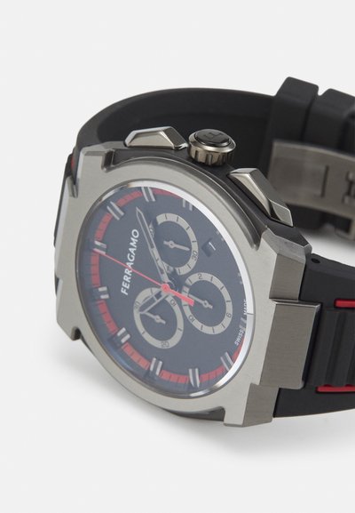 Black rubber strap watch with a stainless steel case, featuring red accents, a black face, three sub-dials, and silver markers.