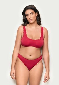 Röd bralette med spetsdetaljer och matchande högmidjade trosor, tillverkade av slitstark tyg, med en avslappnad passform och blommig spetsaccent.