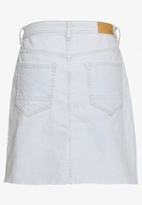 Gonna di jeans azzurro chiaro con taglio dritto, orlo sfrangiato e due tasche posteriori. Presenta un patch in pelle color cuoio sulla vita.