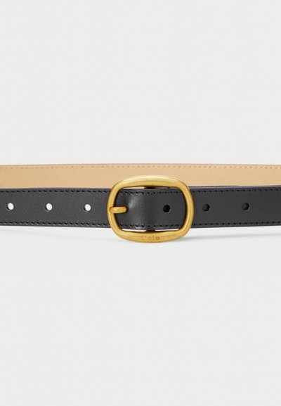 Schwarzer Ledergürtel mit einer goldenen rechteckigen Schnalle, die gleichmäßig verteilte Löcher aufweist. Die Rückseite ist tanfarben und sorgt für ein zweifarbige Design.