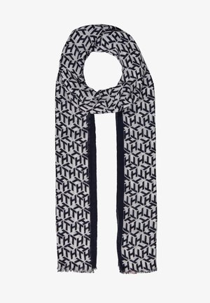 Długi prostokątny szalik z czarno-białym geometrycznym wzorem i czarnymi pionowymi paskami wzdłuż brzegów, z lekko postrzępionymi końcami.