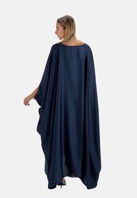 Mörkblå kaftan tillverkad av ett mjukt tyg, med en lös, flödande design, breda ärmar och rund halsringning, som når till mitten av vaden.