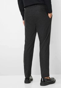 Grijze textuur broek met een recht model, voorzien van zijzakken, een achterzak en een stof van gemiddelde dikte. Gecombineerd met zwarte schoenen.