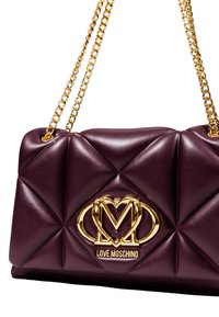 Borsa a tracolla in pelle trapuntata color bordeaux con una catena dorata, dotata di una placca con logo dorato sul davanti e una finitura liscia e lucida.