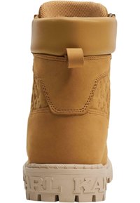 Brune suedes ankelstøvler med polstret krave, teksturert sidepanel og en chunky beige såle med preget merke.