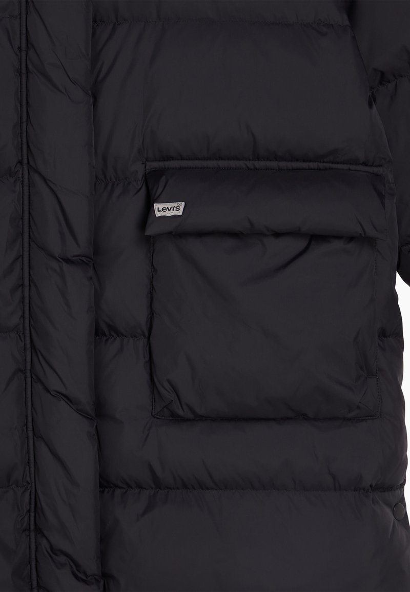Czarna kurtka puchowa z pikowanymi sekcjami, z przednią kieszenią i metką Levi's. Wykonana z błyszczącego, gładkiego materiału, o miękkiej teksturze.