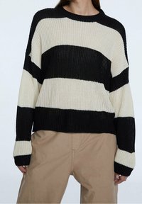 Maglione lavorato a maglia con strisce orizzontali alternate in nero e crema, scollatura rotonda e vestibilità morbida con polsini e orlo a coste.