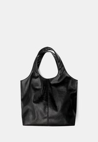 Schwarze Leder-Tasche mit weicher Textur, breiten Schulterriemen und einem schlichten Design. Verfügt über eine zentral verlaufende Naht, die vertikal angebracht ist.