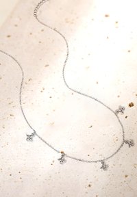 Srebrny naszyjnik o łańcuszku z czterema akcentami przypominającymi diamenty, elegancki design z delikatną teksturą i symetrycznym rozmieszczeniem ozdób.