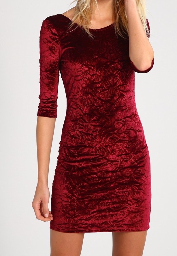 Robe en velours rouge avec des manches ¾, silhouette ajustée et texture froissée. Design longueur genoux avec un décolleté rond.