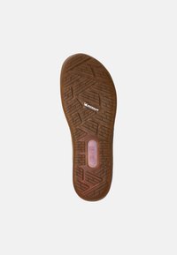 Suela de zapato de goma marrón con un patrón de relieve y logotipo. Presenta una sección de amortiguación transparente y un nombre de marca moldeado.