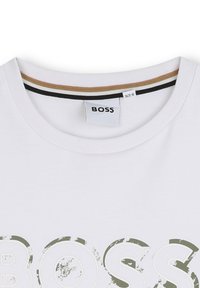 Witte katoenen T-shirt met ronde hals, voorzien van een grafische "BOSS"-logo in olijfgroen, en een contrasterende gestreepte halsband in zwart en goud.
