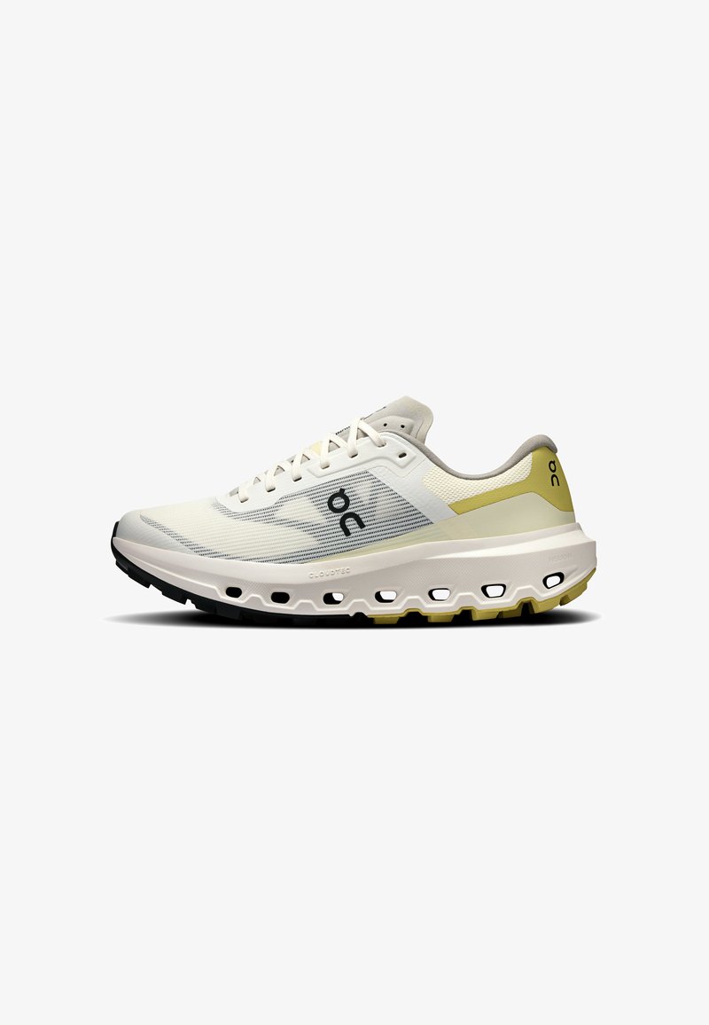 Chaussure de course beige clair avec lacets blancs, tige en mesh respirant, semelle épaisse et rembourrée avec trous de ventilation, et accents jaunes subtils.