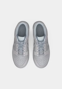 Lysegrå sneakers med overdel i glatt skinn, perforert tåboks og ton-i-ton snøring, med en myk grå innredning og logodetaljer.