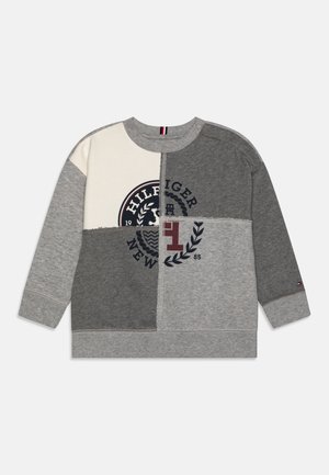 Felpa patchwork grigia e crema con un logo circolare che presenta la scritta "HILFIGER" e un design a foglia, polsini a costine e collo a girocollo.