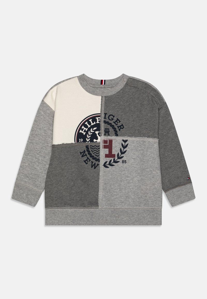 Felpa patchwork grigia e crema con un logo circolare che presenta la scritta "HILFIGER" e un design a foglia, polsini a costine e collo a girocollo.