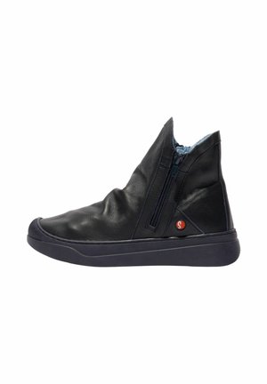 Zwart leren enkellaarsje met zijrits, rubberen zool en klein rood rond logo vlak bij de hiel, zijaanzicht op witte achtergrond.