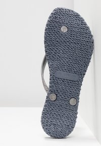 Sole of a dark gray sandal with textured rope pattern and embossed brand name, size label, and three visible round metal rivets.