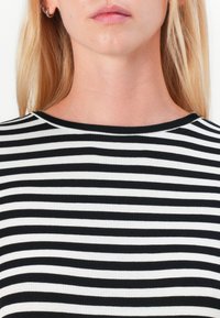 Black and white striped top with a crew neckline. Ribbed texture, close-fitting design, showing upper chest area.
