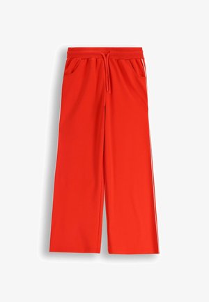 Czerwone, szerokie dresy wykonane z miękkiego materiału, z elastycznym pasem, sznurkiem i bocznymi kieszeniami. Posiadają białe boczne paski.