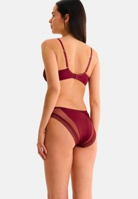 Ensemble de lingerie bordeaux comprenant un soutien-gorge et une culotte. Le soutien-gorge possède des bretelles fines réglables et une finition lisse, tandis que la culotte présente des accents en dentelle et des panneaux en mesh.