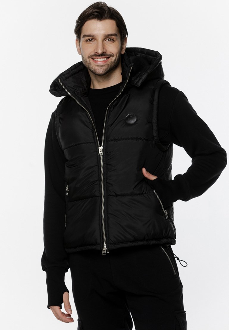 Czarna ocieplana kamizelka z kapturem, z przodem na zamek, bocznymi kieszeniami i okrągłym logo na piersi. Gładka, błyszcząca powierzchnia materiału.