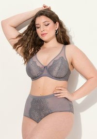 Grijze lingerieset bestaande uit een kanten beha met transparante cups en hoge slipjes, versierd met ingewikkelde patronen en zachte texturen.