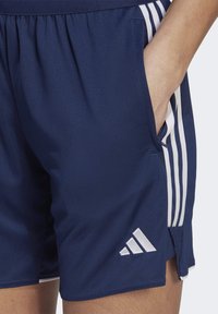 Pantalones cortos deportivos en color navy con una textura lisa, cintura elástica, bolsillos laterales y acentos en tres franjas blancas a lo largo de los lados.