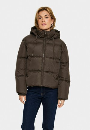 Brown puffer jacket with a hood, zip closure, and drawstring details. Boxy shape with quilted pattern and front pockets. Worn with dark jeans.