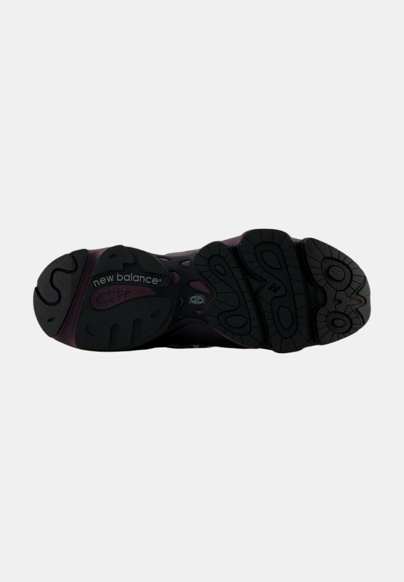 Baskets New Balance avec une semelle en caoutchouc noir présentant un motif de grip prononcé, des accents violets foncés et des détails de surface texturée.