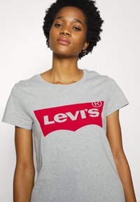 Grå bomulds t-shirt med et stort rødt Levi's-logo med hvid skrift. Korte ærmer, rund hals og en afslappet pasform.