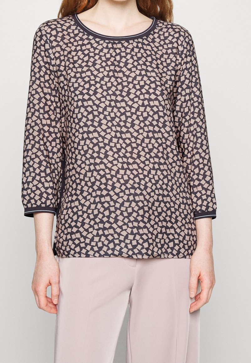 Maglietta a maniche lunghe con motivo geometrico di quadrati beige e marrone scuro, con scollatura rotonda e bordi neri, realizzata in tessuto leggero.