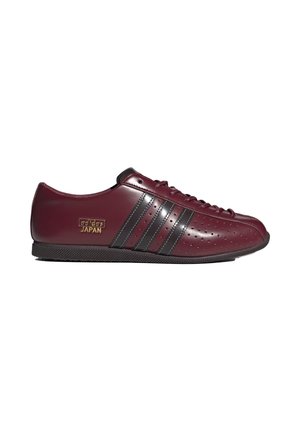 Sneaker Adidas Japan rosso scuro con strisce nere, punta traforata, chiusura con lacci e suola nera, vista di lato.