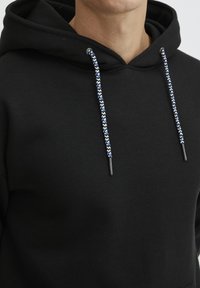Sudadera negra con cordón que presenta un trenzado de patrones en azul y blanco. Diseñada con una textura suave y un ajuste clásico.