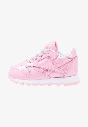 Pink blank lille børnesneaker med hvide snørebånd og sål, med syninger og et lille britisk flaglogo på siden.
