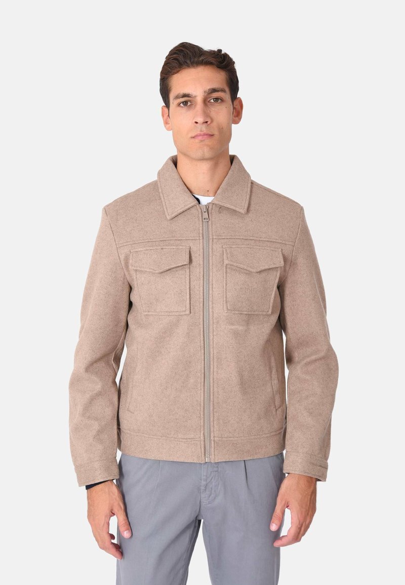 Giacca in feltro beige con zip frontale, due tasche sul petto e colletto classico. Presenta una finitura testurizzata e un design a taglio dritto.