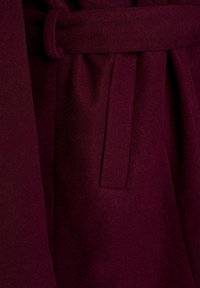 Deep burgundy wool coat fabric with a belt loop and a vertical slit pocket on the front section.