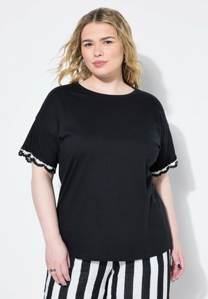 Zwarte korte mouwen shirt met geschulpte witte en zwarte kantafwerking op de mouwen, gemaakt van een zachte stof, ronde halslijn, ontspannen pasvorm.