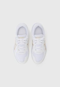 Weiße Mesh-Sportschuhe mit strukturierter Oberfläche, ausgestattet mit einem goldenen Logo, Schnürsenkeln und einer hellen Sohle. Einfaches Design mit minimalen Akzenten.