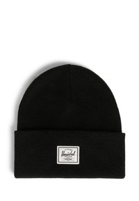Gorro de punto negro con puño doblado, que presenta una etiqueta rectangular blanca con texto negro en un lado. Tejido suave y texturizado.