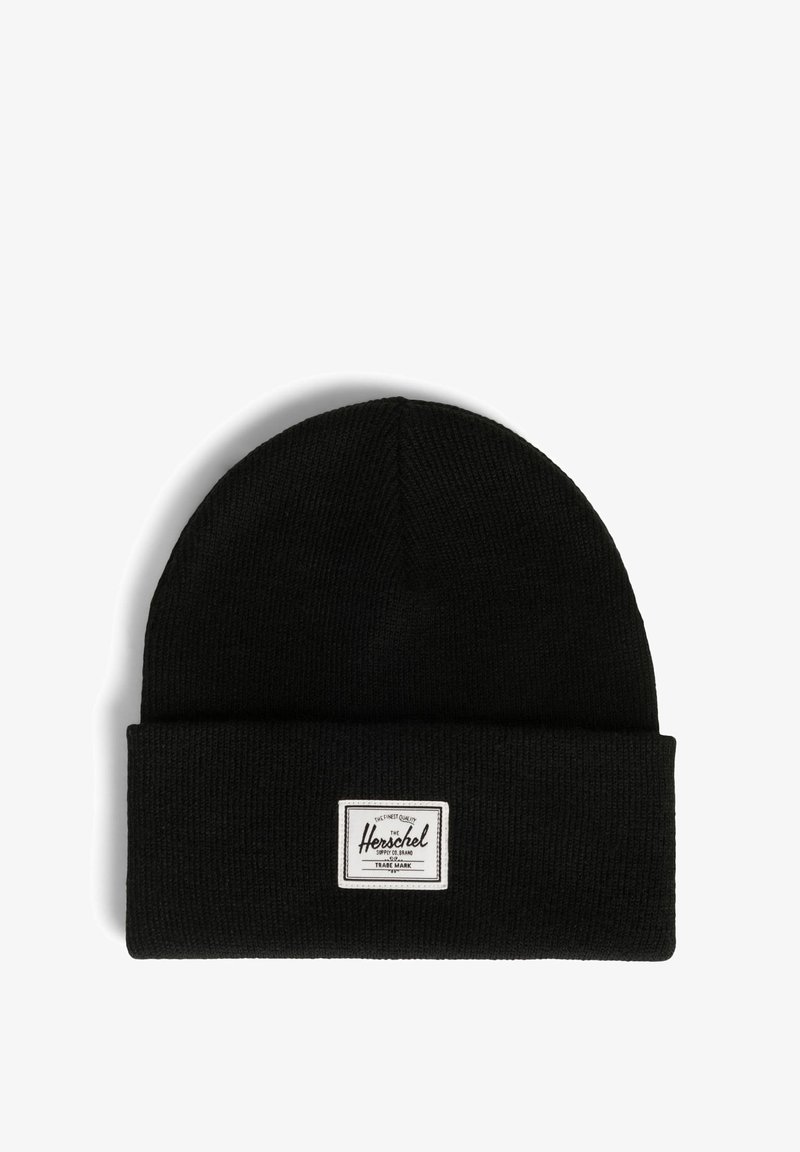 Gorro de punto negro con puño doblado, que presenta una etiqueta rectangular blanca con texto negro en un lado. Tejido suave y texturizado.