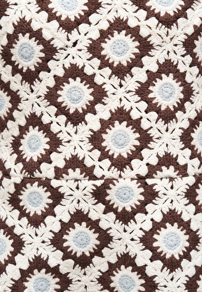 Πλεκτό ύφασμα με μοτίβο διαμαντιού σε καφέ και εκρού νήμα, με κυκλικά ανοιχτό γκρι κέντρα σε κάθε σχήμα διαμαντιού.