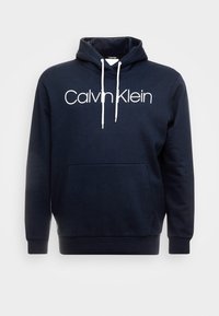 Felpa con cappuccio blu navy in misto cotone, dotata di tasca a marsupio frontale e lacci bianchi, con il logo "Calvin Klein" sul petto.