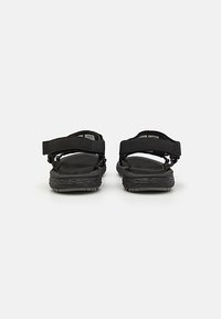 Black sandals with adjustable straps and textured soles. Features padded footbeds and a simple, functional design.