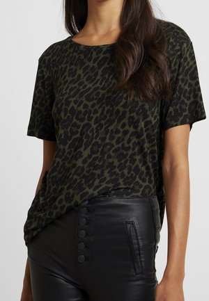 Olivově zelené tričko s leopardím potiskem a krátkým rukávem, s kulatým výstřihem, ve spojení s černými kalhotami s vysokým pasem a knoflíkovými detaily.